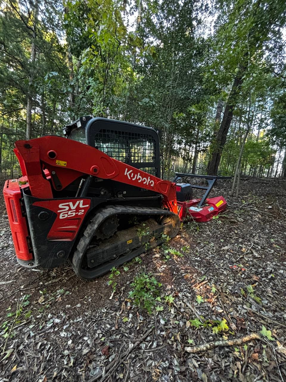 Heyward Enterprise Kubota SVL65-2 track loader with a forestry mulching head on a wooded lot